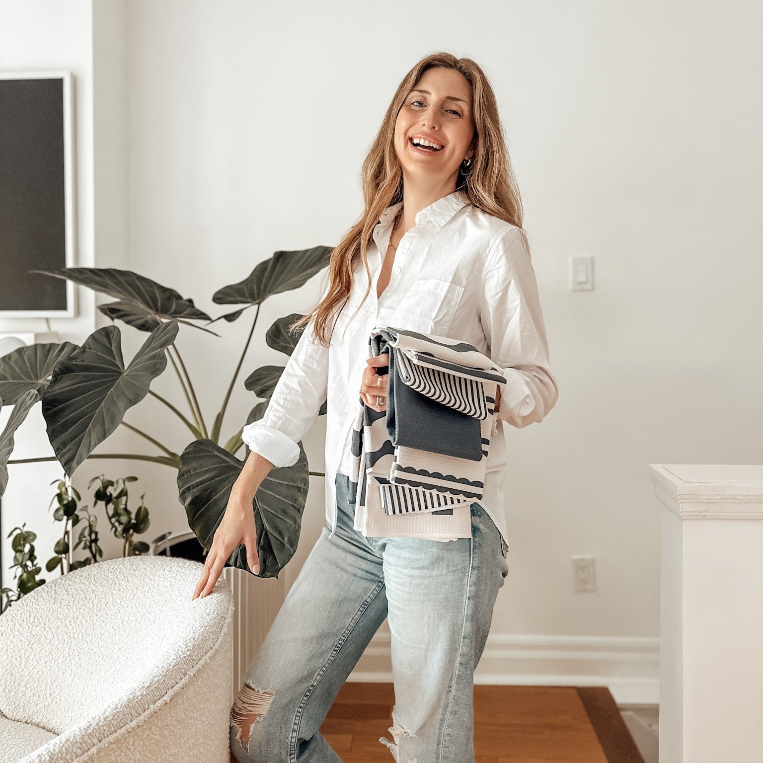 Disch Towels Founder Sasha Mazzuca Holding Blue and White Striped Tea Towels
