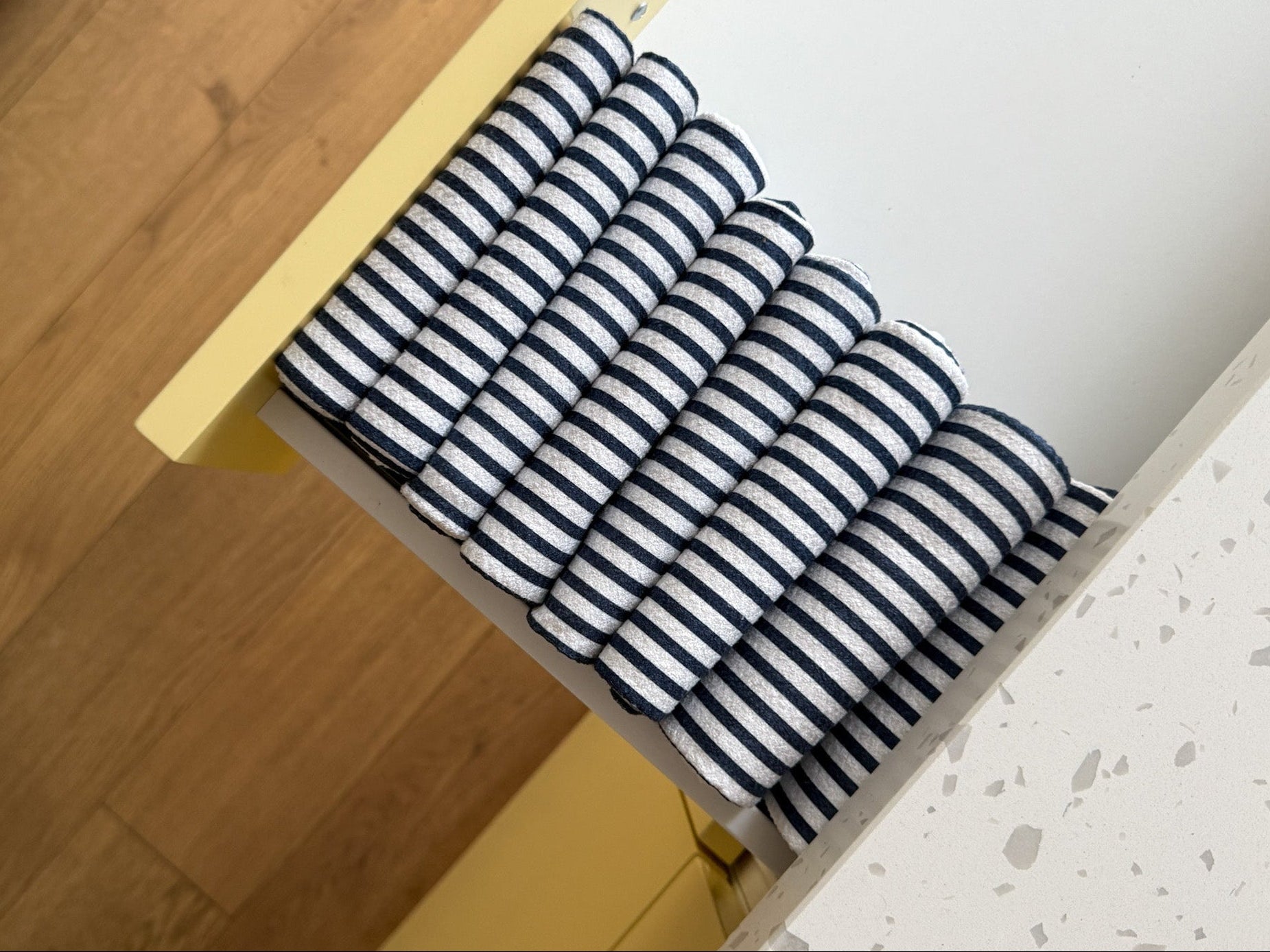 Organized Stack of folded blue and white striped towels in an open drawer.